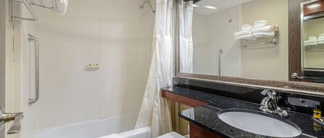 A bathroom with a bathtub, toilet, sink, and a mirror.