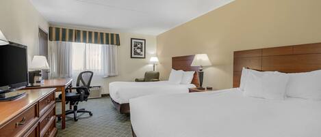 Quarto de hotel com duas camas, uma escrivaninha, televisão e uma cadeira.