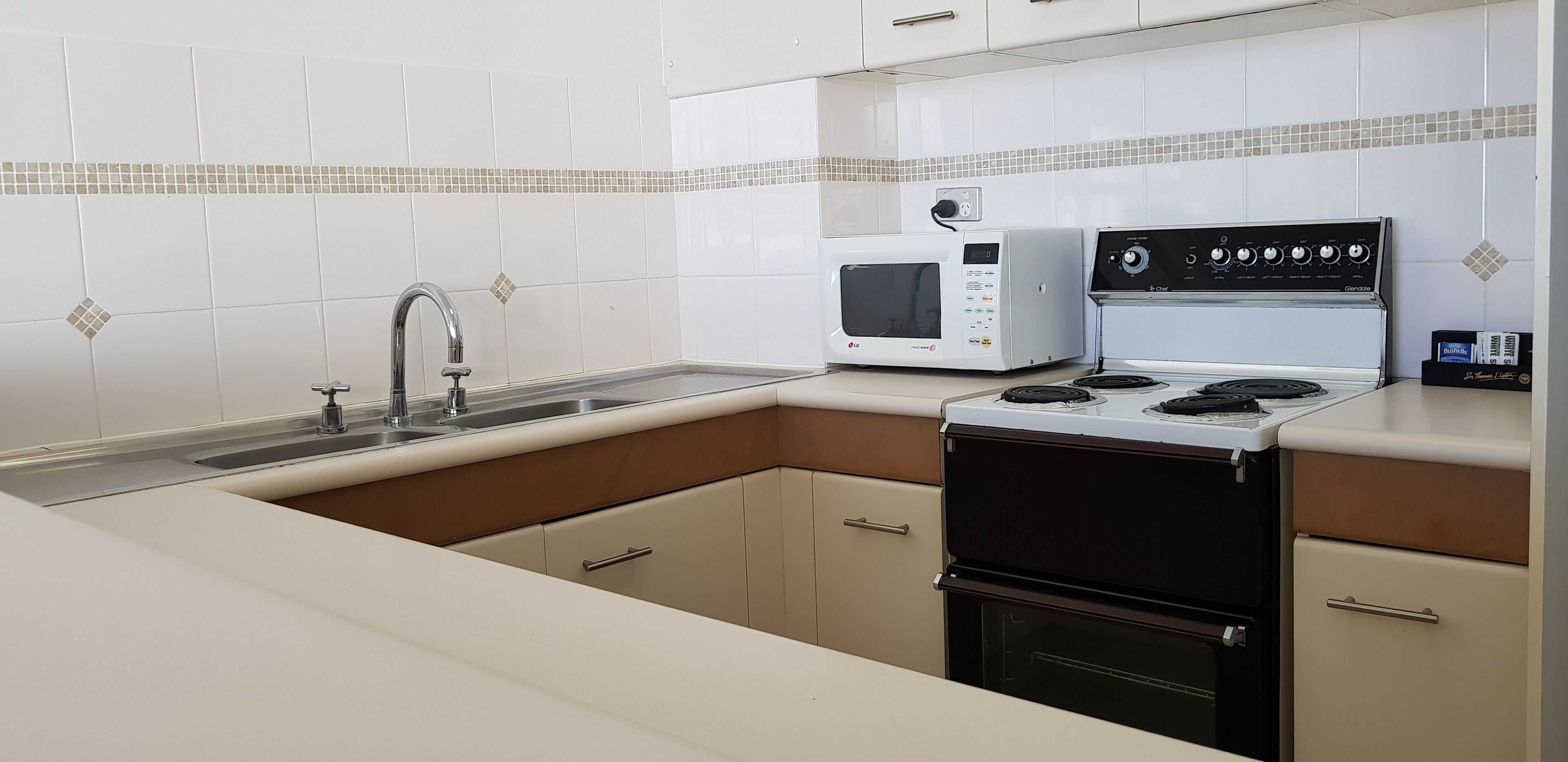 A compact kitchen with a sink, a microwave, and a stove.