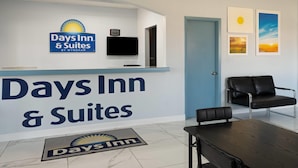 Vastaanottoalue, jossa on Days Inn & Suites -kyltti, litteänäyttöinen televisio, sininen ovi sekä oleskelualue, jossa on musta nahkasohva ja puinen pöytä.