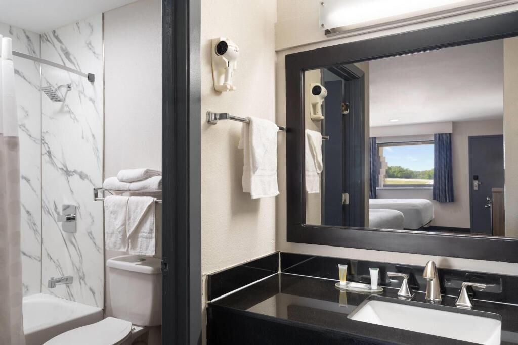 A modern bathroom with a marble shower, a large mirror, and a black countertop sink.