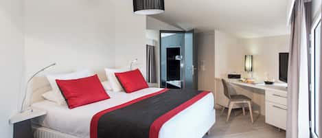 A modern hotel room with a large bed, a desk, and a computer.