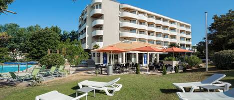 A hotel with outdoor seating and a pool.