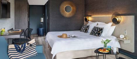 Una habitación de hotel moderna con una cama grande, un escritorio, un sofá y una mesita con desayuno.