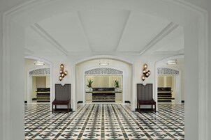 A spacious lobby with a patterned floor, a reception desk, and seating areas.