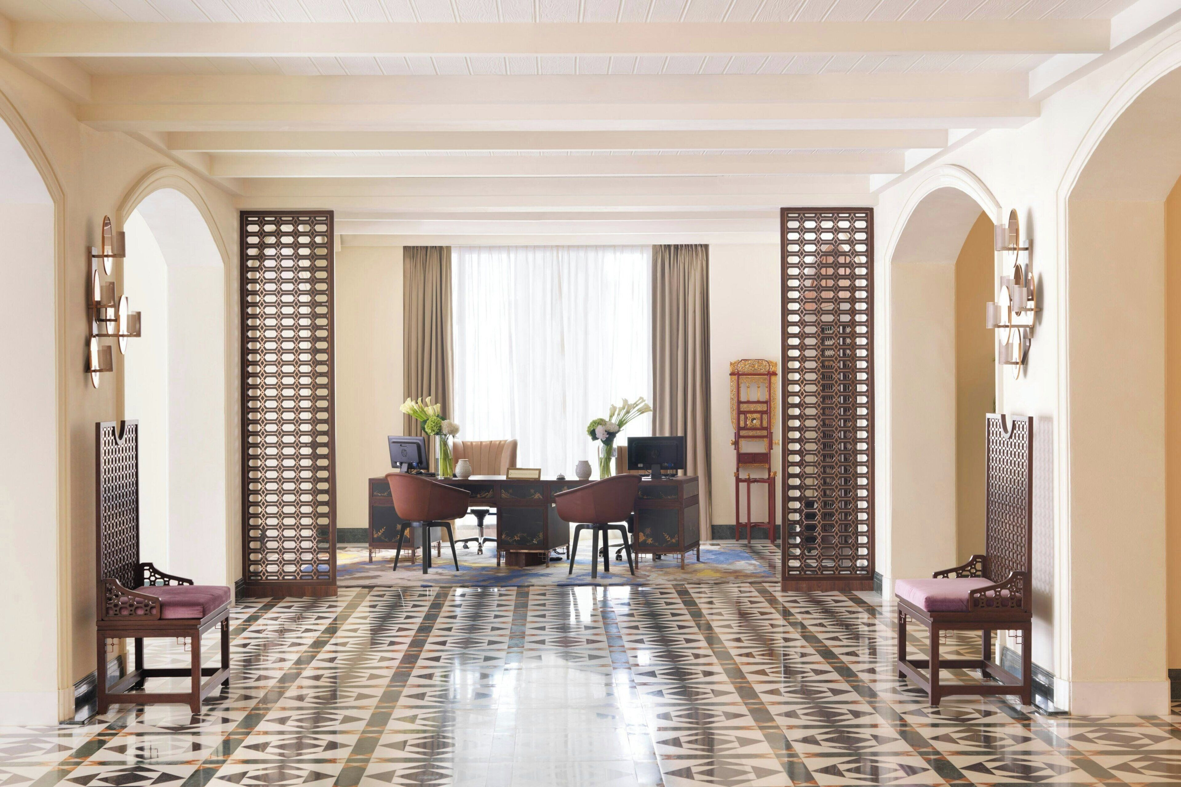 Un vestíbulo de hotel con mostrador de recepción, zona de estar y paneles decorativos.