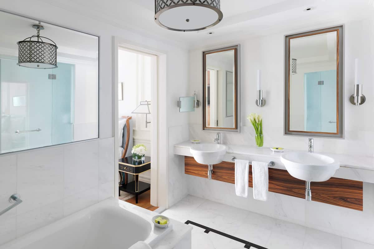 A modern bathroom with a bathtub, two sinks, and a large mirror.