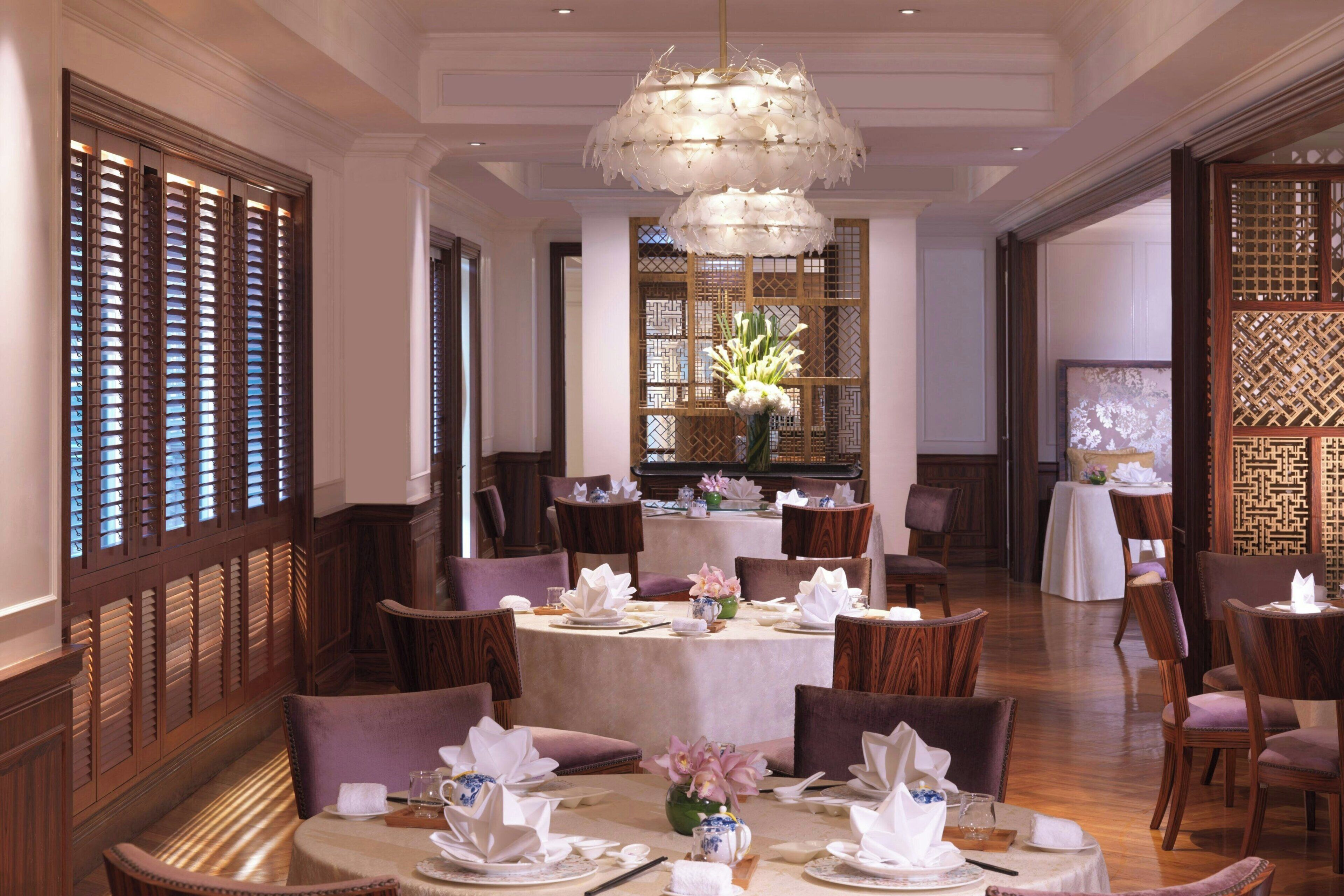 Comedor con mesas redondas, sillas y un candelabro decorativo.