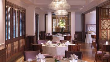 Comedor con mesas redondas, sillas y un candelabro decorativo.