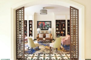 A living room with a sofa, two armchairs, a coffee table, a patterned rug, and a bookshelf.