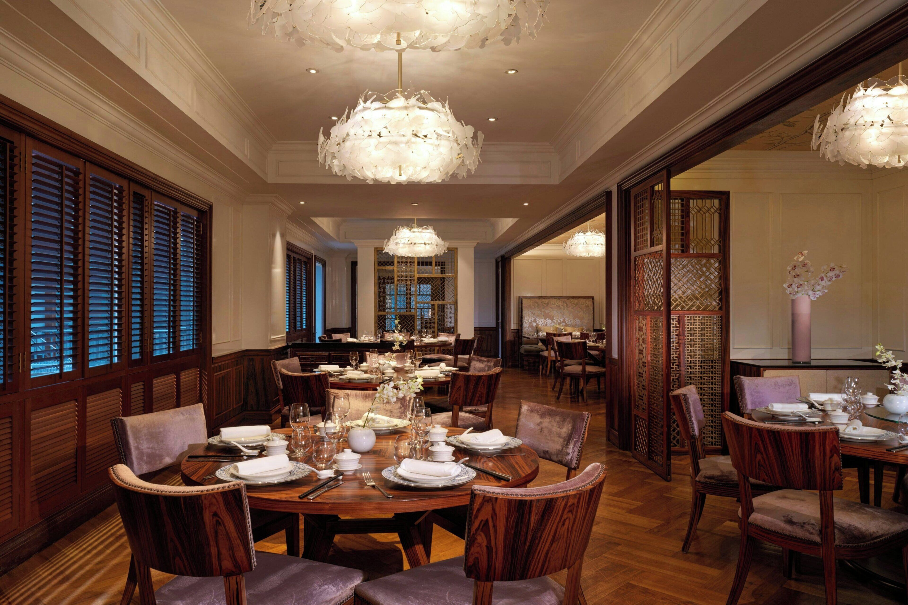 A formal dining room with wooden furniture, chandeliers, and traditional decor.
