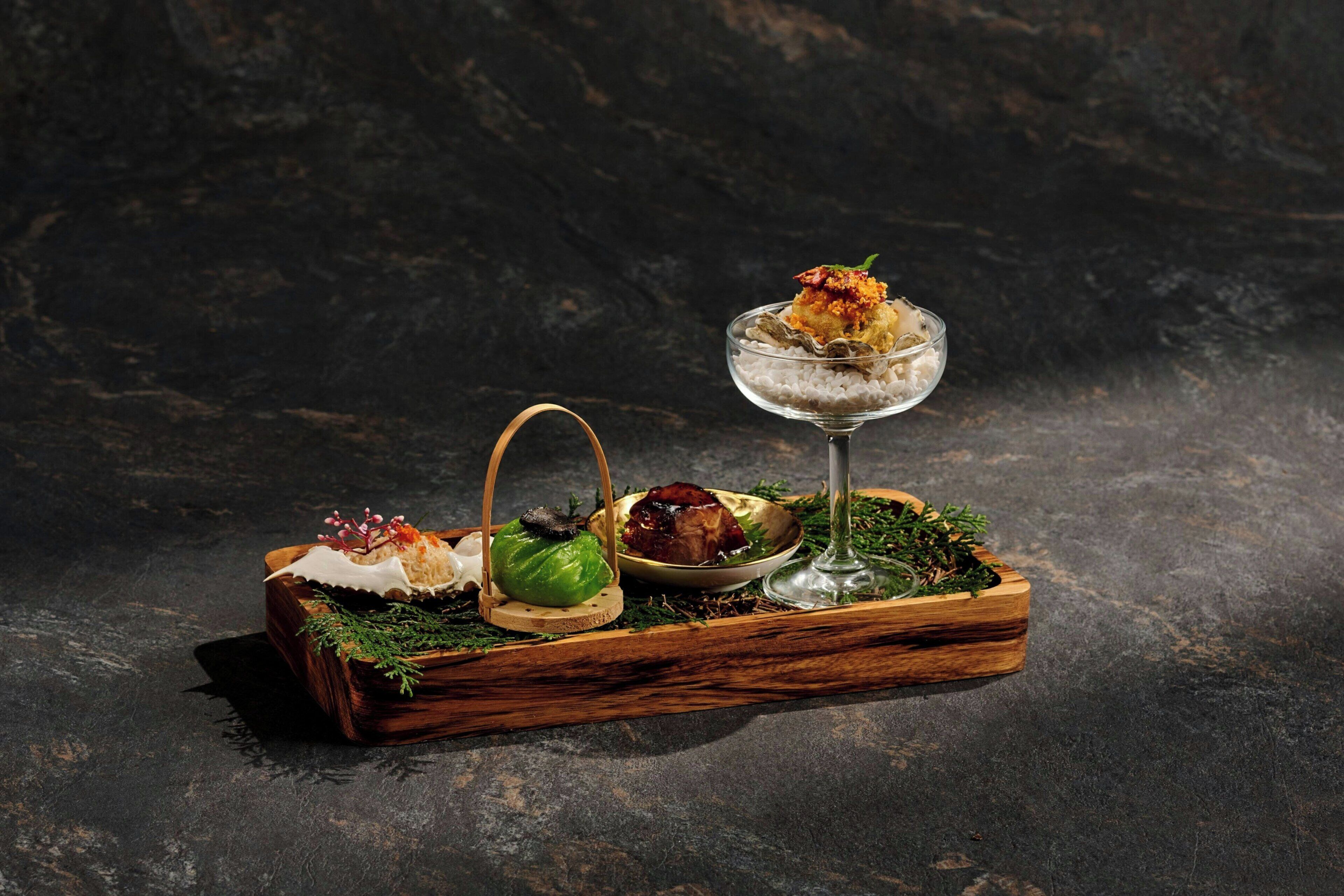 A wooden tray with food items and a glass of water on a dark surface.
