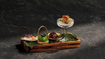 A wooden tray with food items and a glass of water on a dark surface.