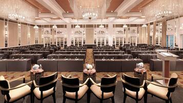 Un amplio salón de conferencias con filas de mesas y sillas, candelabros y un atril.