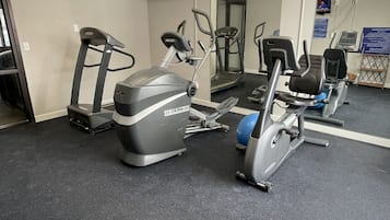 A gym with stationary bikes, treadmills, and a mirrored wall.