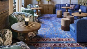 A spacious lounge with a checkered coffee table, plush sofas, and a large mirror.