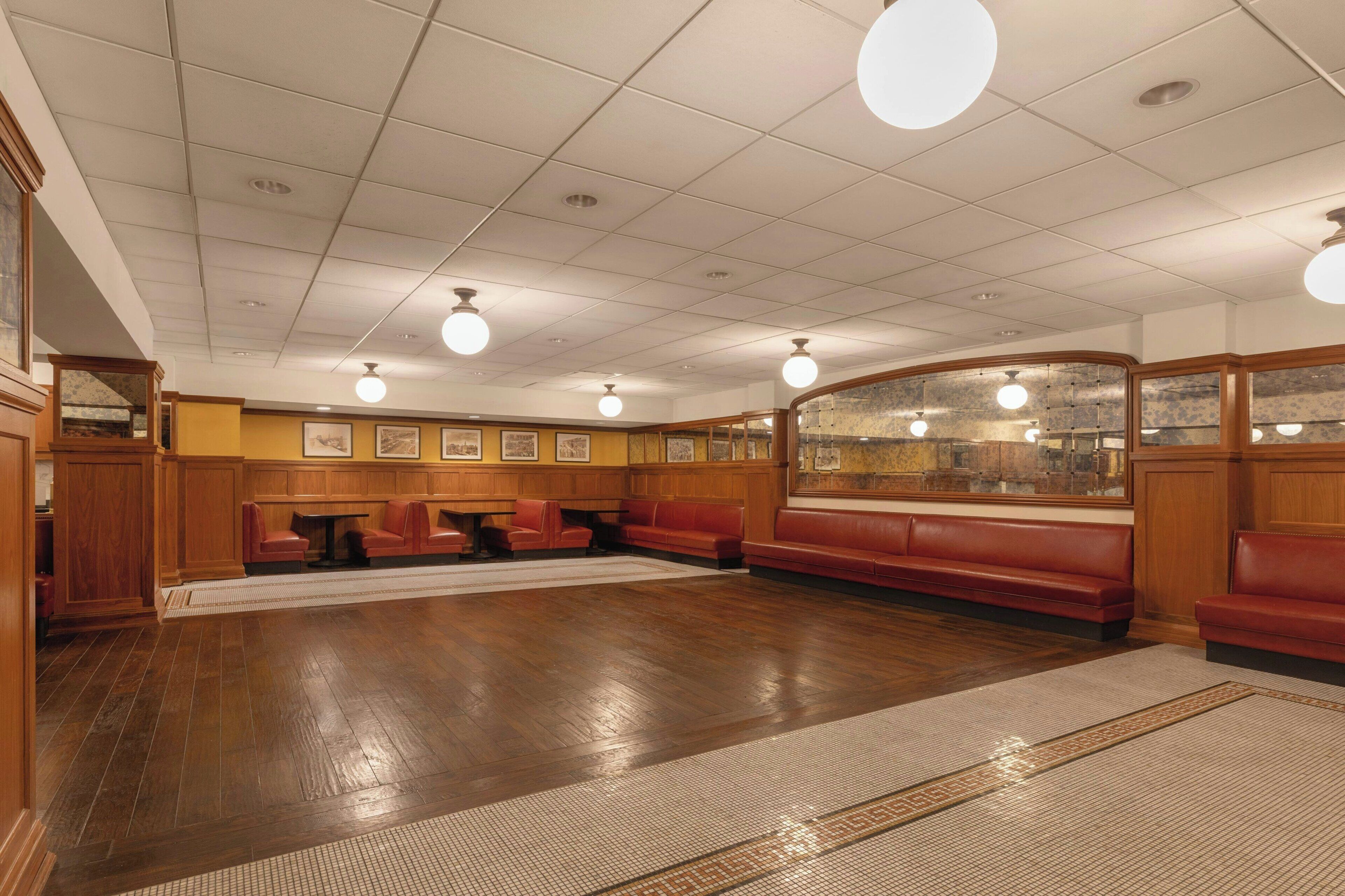 A spacious room with wooden paneling, a long bench seating area, and a patterned floor.