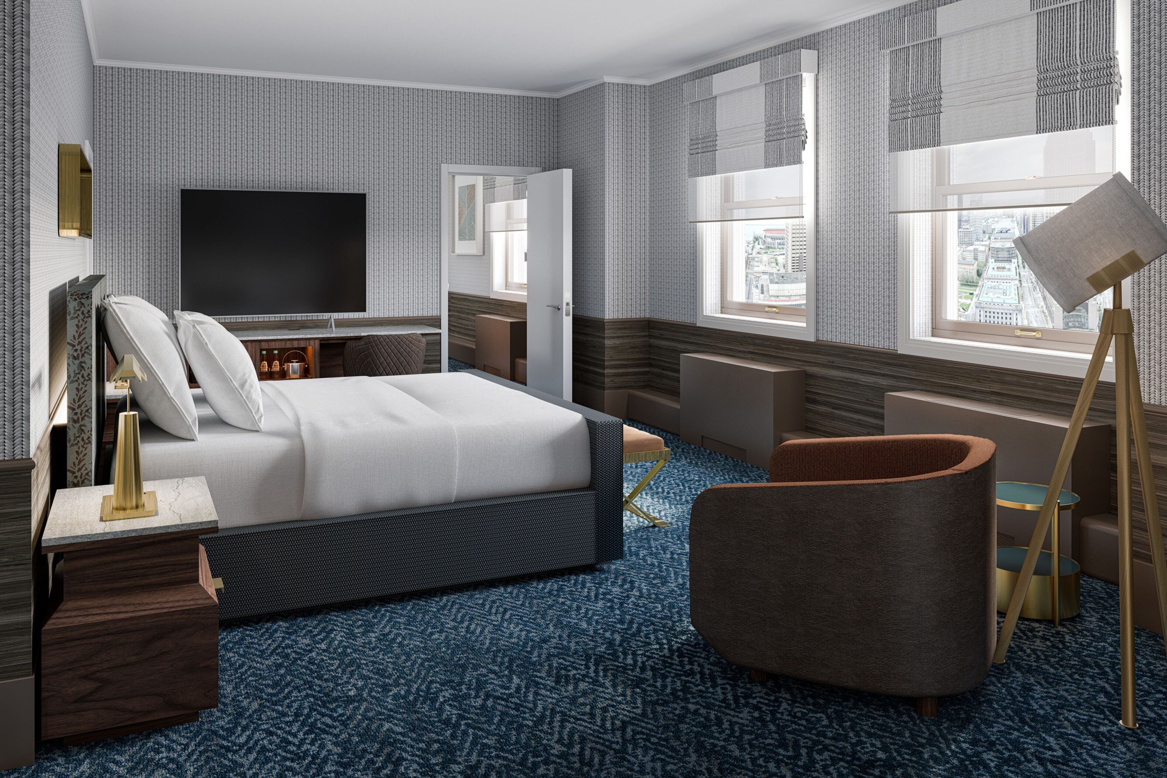 A modern hotel room with a large bed, a flat-screen TV, a desk, and a chair.