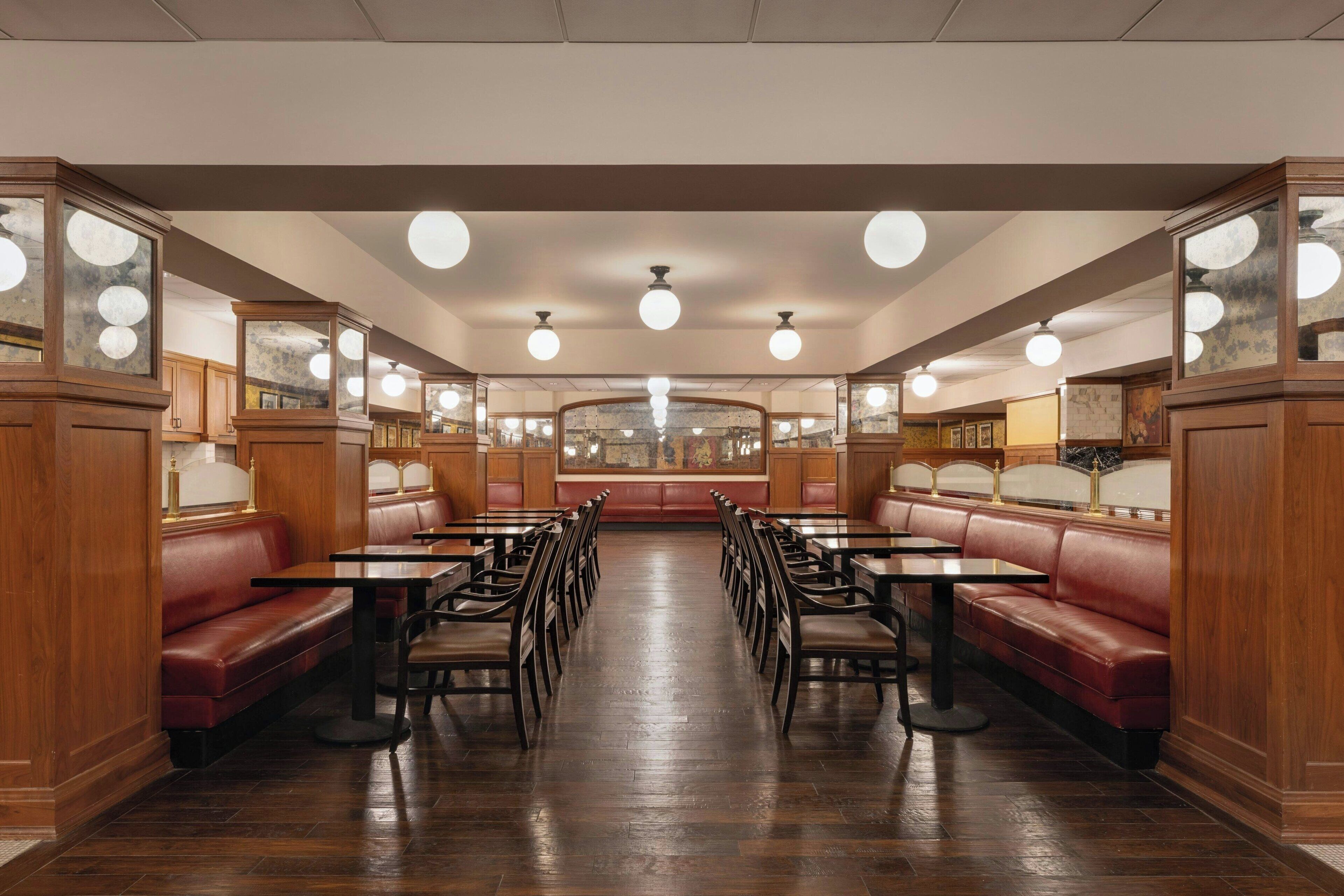 A restaurant interior with booths and tables, wooden paneling, and a central ceiling light fixture.