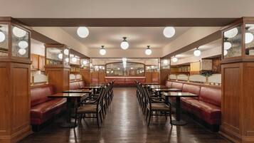 A restaurant interior with booths and tables, wooden paneling, and a central ceiling light fixture.