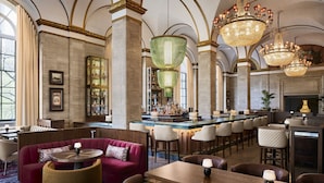 A bar area with high-backed chairs, a bar counter, and a seating area with sofas and tables.