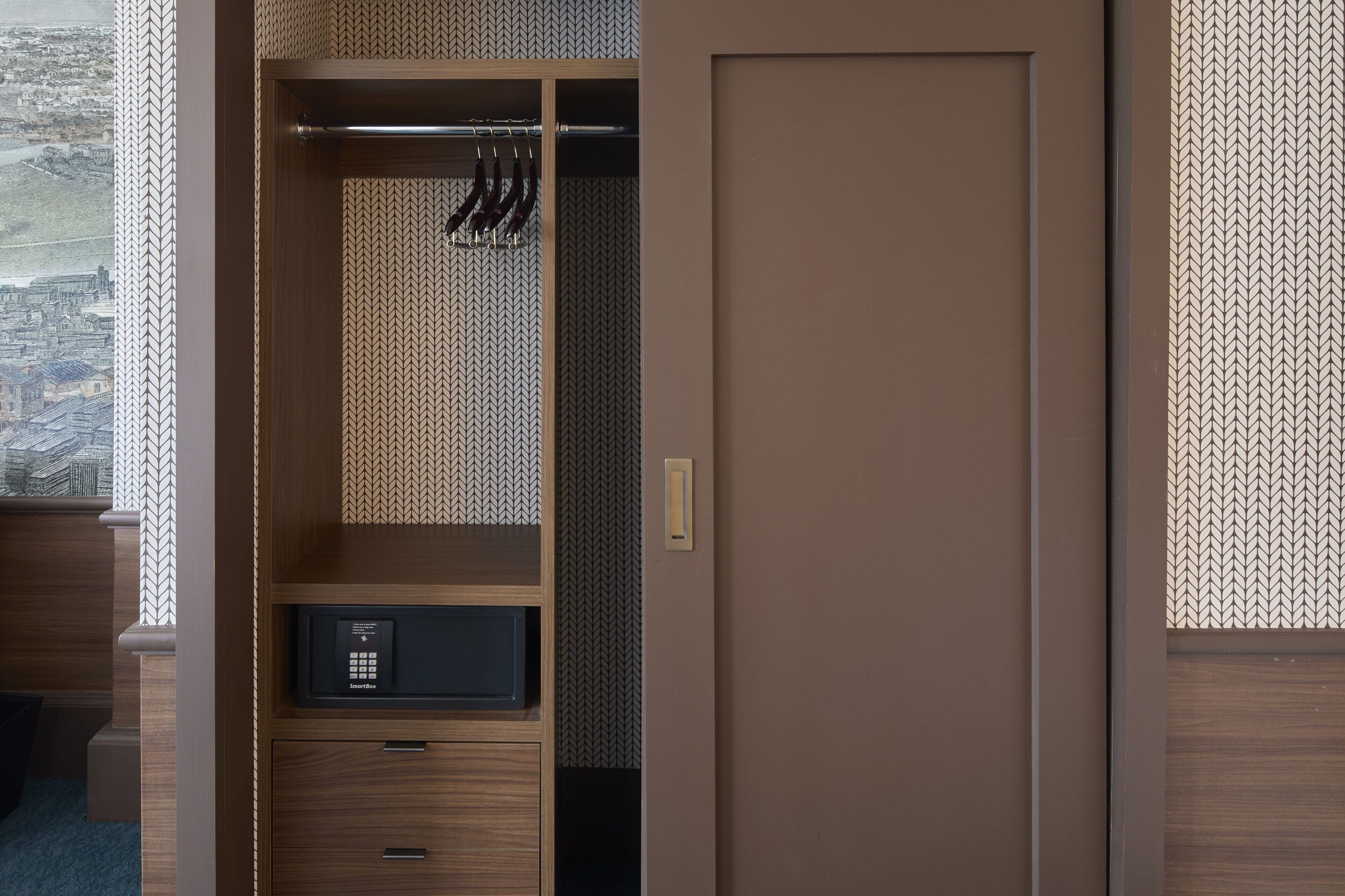 Une chambre d’hôtel avec une armoire en bois, un minibar et une vue sur le paysage urbain par la fenêtre.
