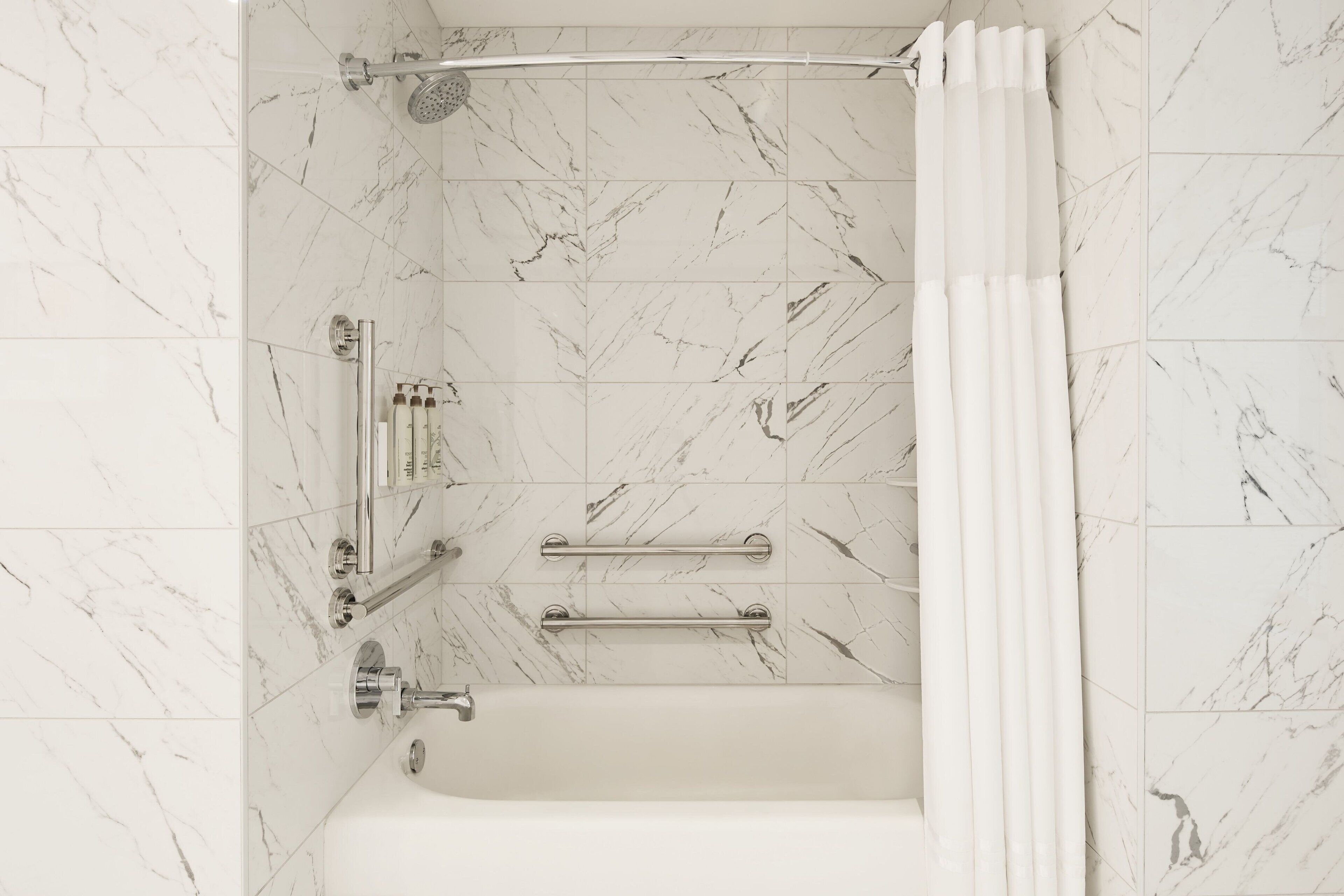 Un baño con bañera, ducha y barra de apoyo.