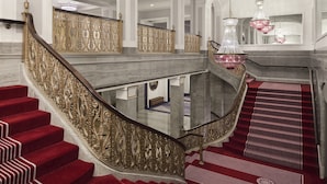 A grand staircase with ornate golden railings and red carpeted steps.