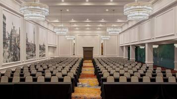 A conference room with rows of chairs, a carpeted floor, and chandeliers.