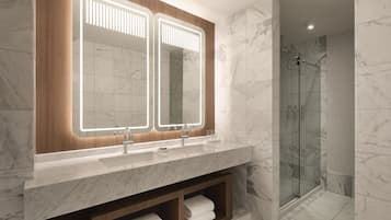 A modern bathroom with a large mirror, two sinks, and a glass-enclosed shower.