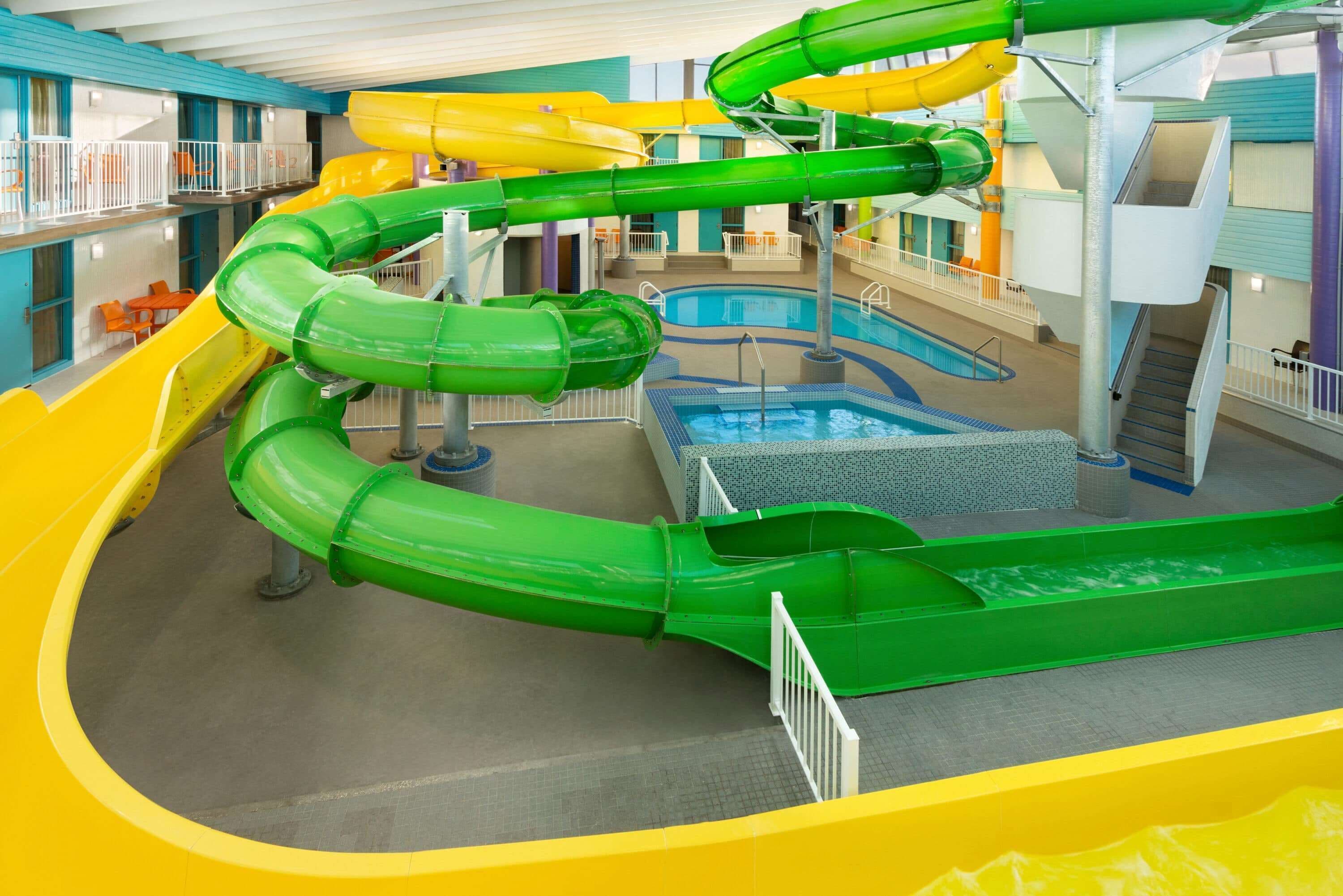 Ein großer Indoor-Wasserpark mit mehreren Wasserrutschen, einem Schwimmbecken und einer mehrstöckigen Konstruktion mit Balkonen.