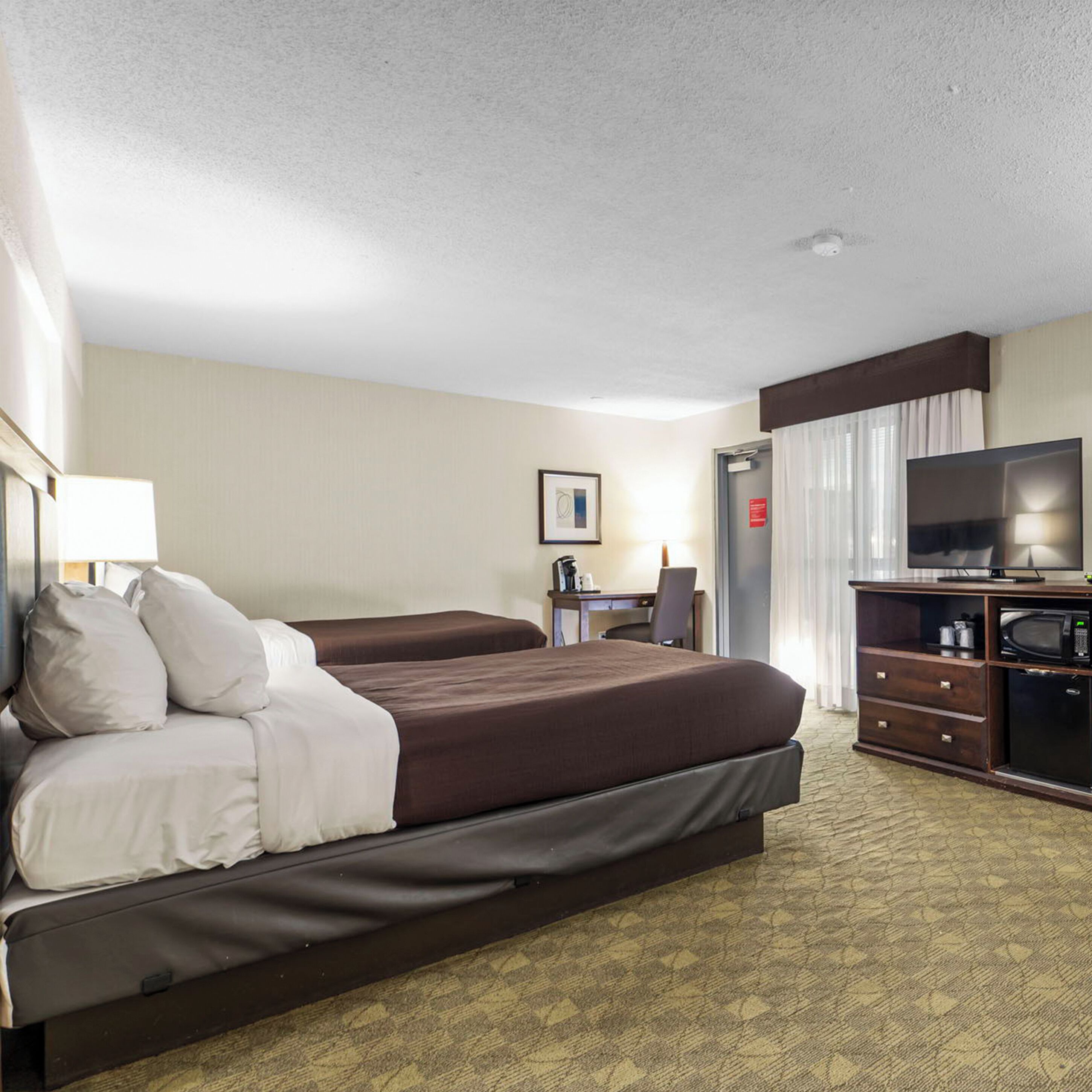 A hotel room with a bed, a desk, a television, and a minibar.
