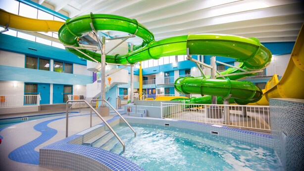 Parque acuático interior con múltiples toboganes y una piscina.