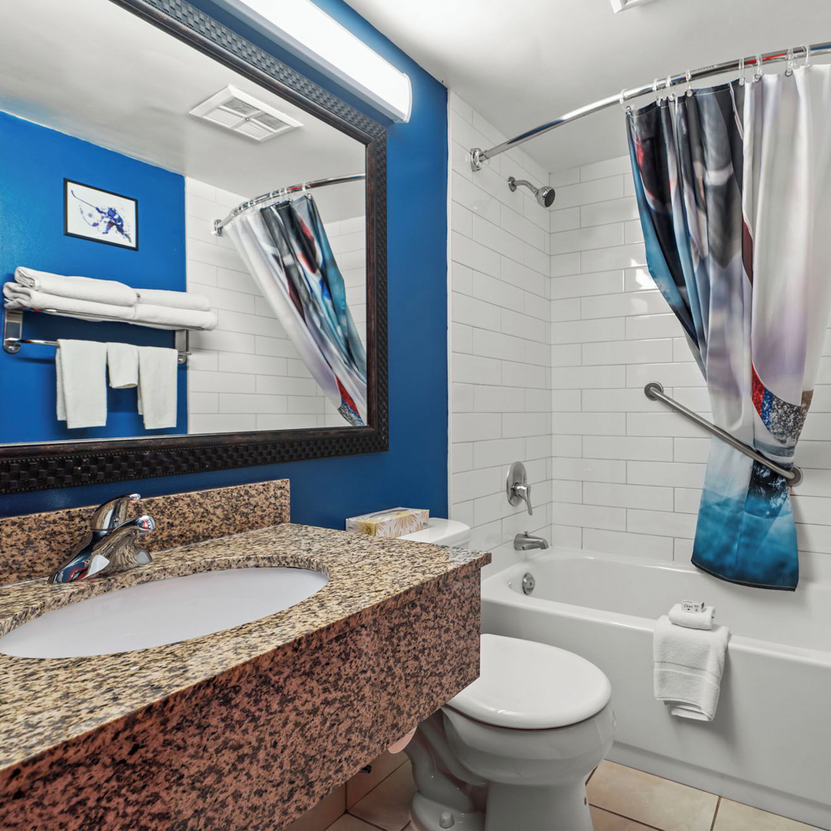 A bathroom with a granite sink, white toilet, and a bathtub.