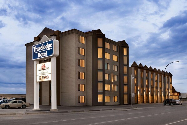 A Travelodge Hotel with a brick facade, multiple windows, and a signboard advertising nearby businesses.