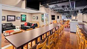 A spacious lounge area with a long wooden table, leather sofas, and wooden chairs.