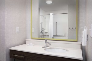 Un baño con lavamanos blanco, un espejo con marco amarillo y una zona de ducha.