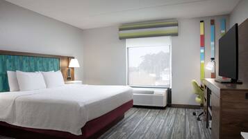 Et hotelværelse med en stor seng, et skrivebord med computer, et vindue med udsigt og et fjernsyn.