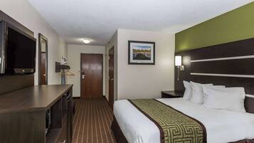 A hotel room with a bed, a TV, a desk, and a framed picture on the wall.