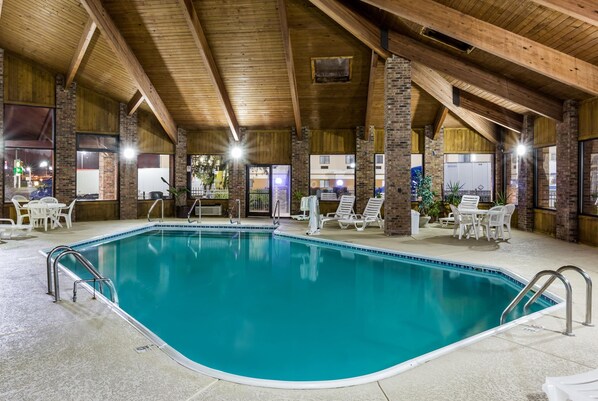 Una piscina interior con agua cristalina, rodeada de sillones de descanso y una estructura de techo de madera.