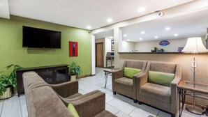 A hotel lobby with a sofa set, a television, a lamp, and a sign for the restaurant. - Baymont by Wyndham Louisville South/Shepherdsville/I 65 (Brooks)