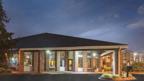 A hotel with a covered entrance, large windows, and a brick facade. - Baymont by Wyndham Louisville South/Shepherdsville/I 65 (Brooks)