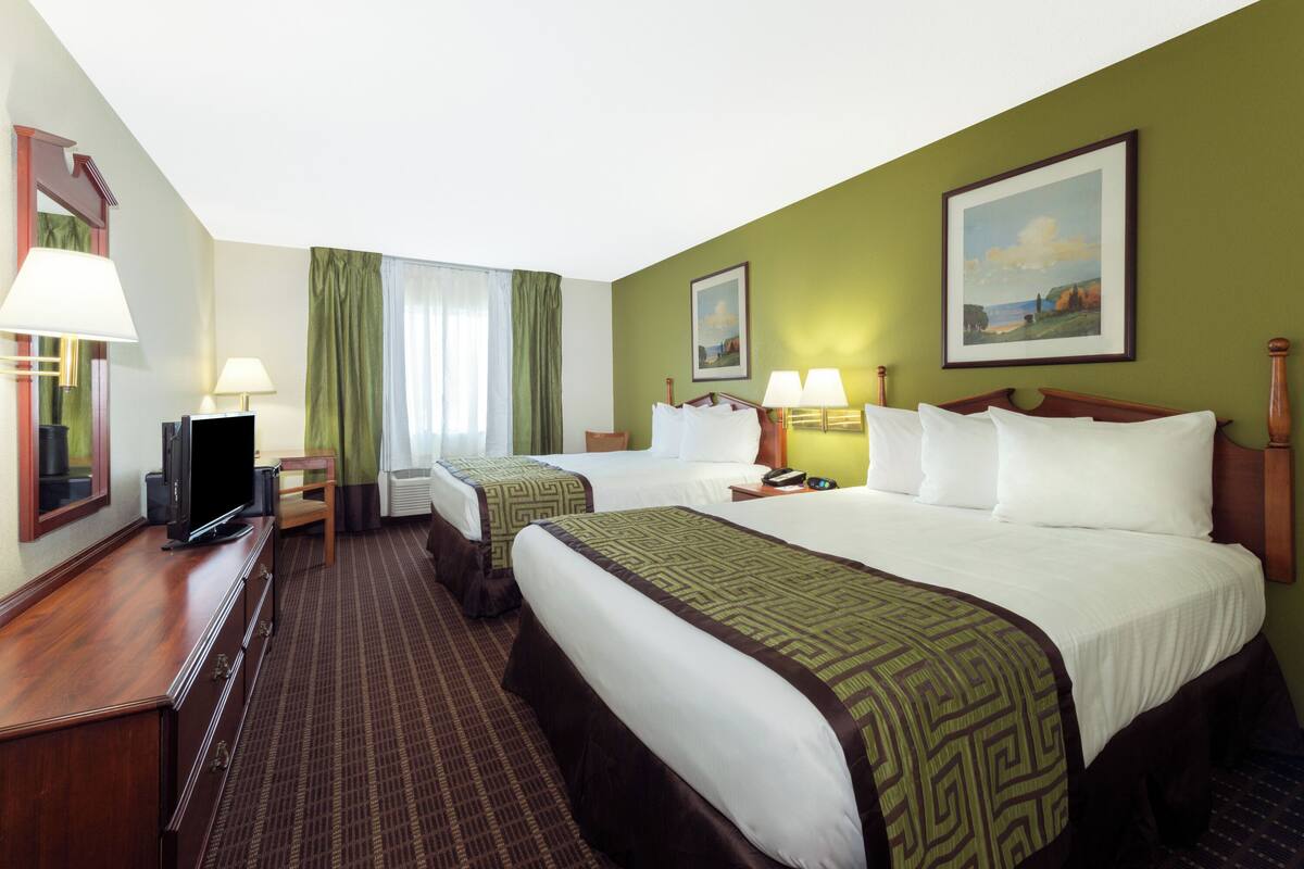 Une chambre d’hôtel avec deux lits, une télévision, un bureau et une chaise.