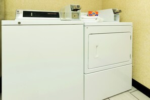 Lavadora y secadora de carga frontal apiladas en un cuarto de lavado, con un panel de control en la parte superior.