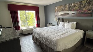 Ett hotellrum med en stor säng, ett skrivbord och ett fönster med gardiner.