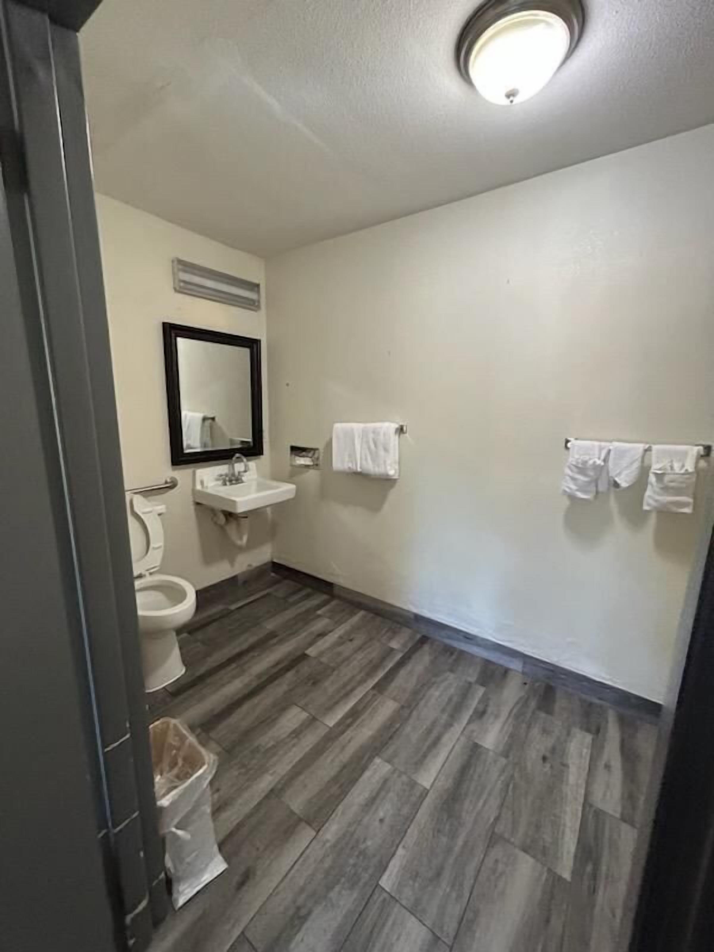 A bathroom with a toilet, sink, mirror, and two towel racks.