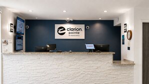 A reception desk with a logo, two computer monitors, a clock, and a welcome sign.