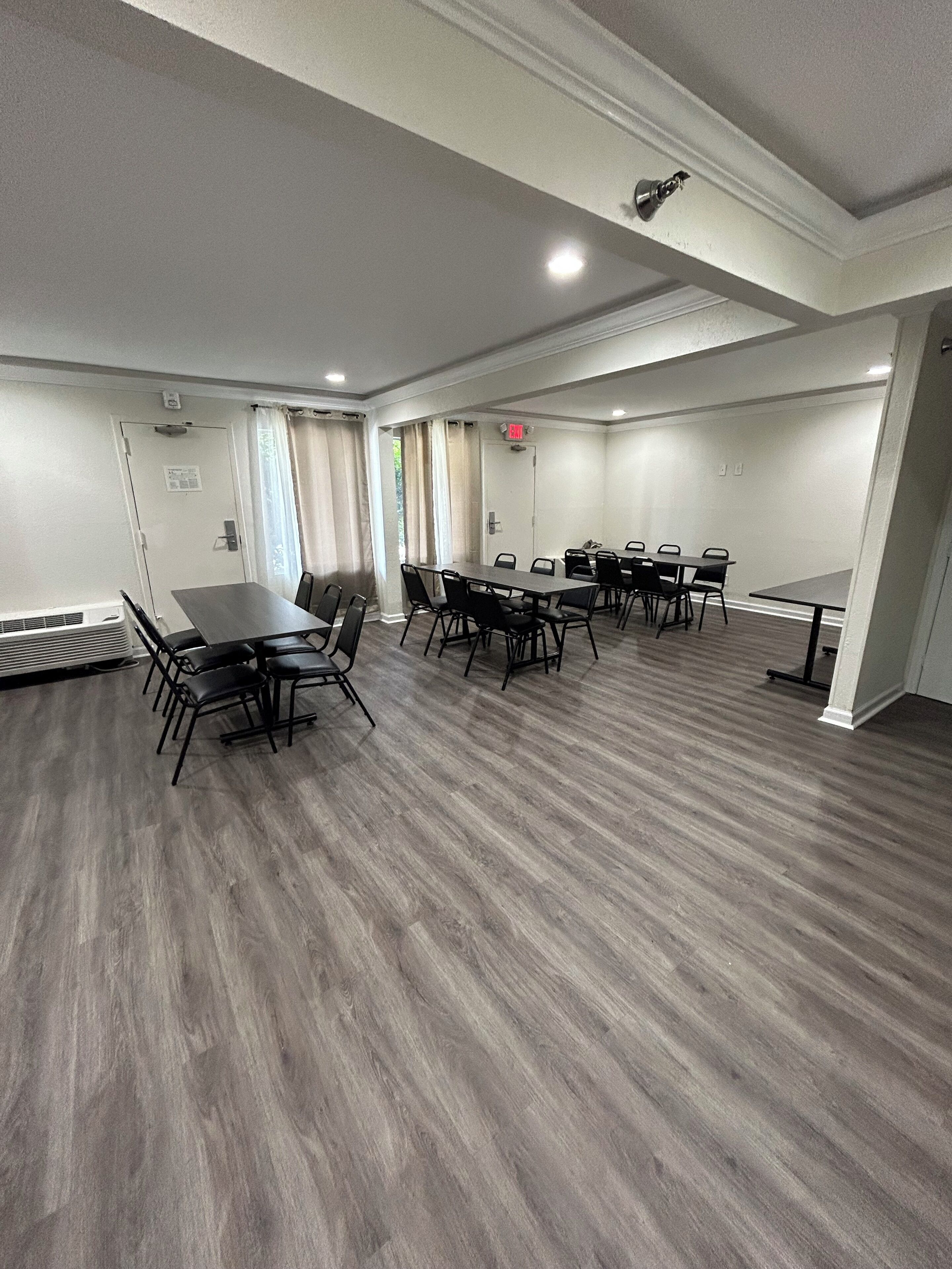A conference room with a large table and chairs, white walls, and a wooden floor.