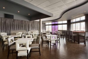 A spacious restaurant with high ceilings, modern seating, and large windows. - Park Inn By Radisson Toronto - Markham (Markham)