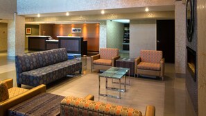 A hotel lobby with a sofa, armchairs, a glass coffee table, and a fireplace. - Park Inn By Radisson Toronto - Markham (Markham)